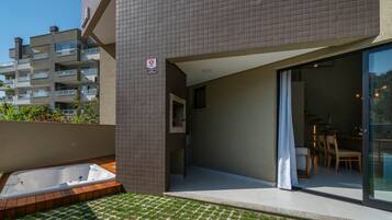 Apartamento moderno com varanda, porta de vidro que dá para uma área de jantar e um pequeno jacuzzi ao ar livre.