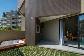 A modern apartment with a balcony, a glass door leading to a dining area, and a small outdoor jacuzzi. - Las Vegas  (Bombinhas)