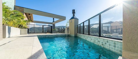 Una piscina en la azotea con agua azul cristalina, rodeada de un diseño arquitectónico moderno y vistas a la ciudad.