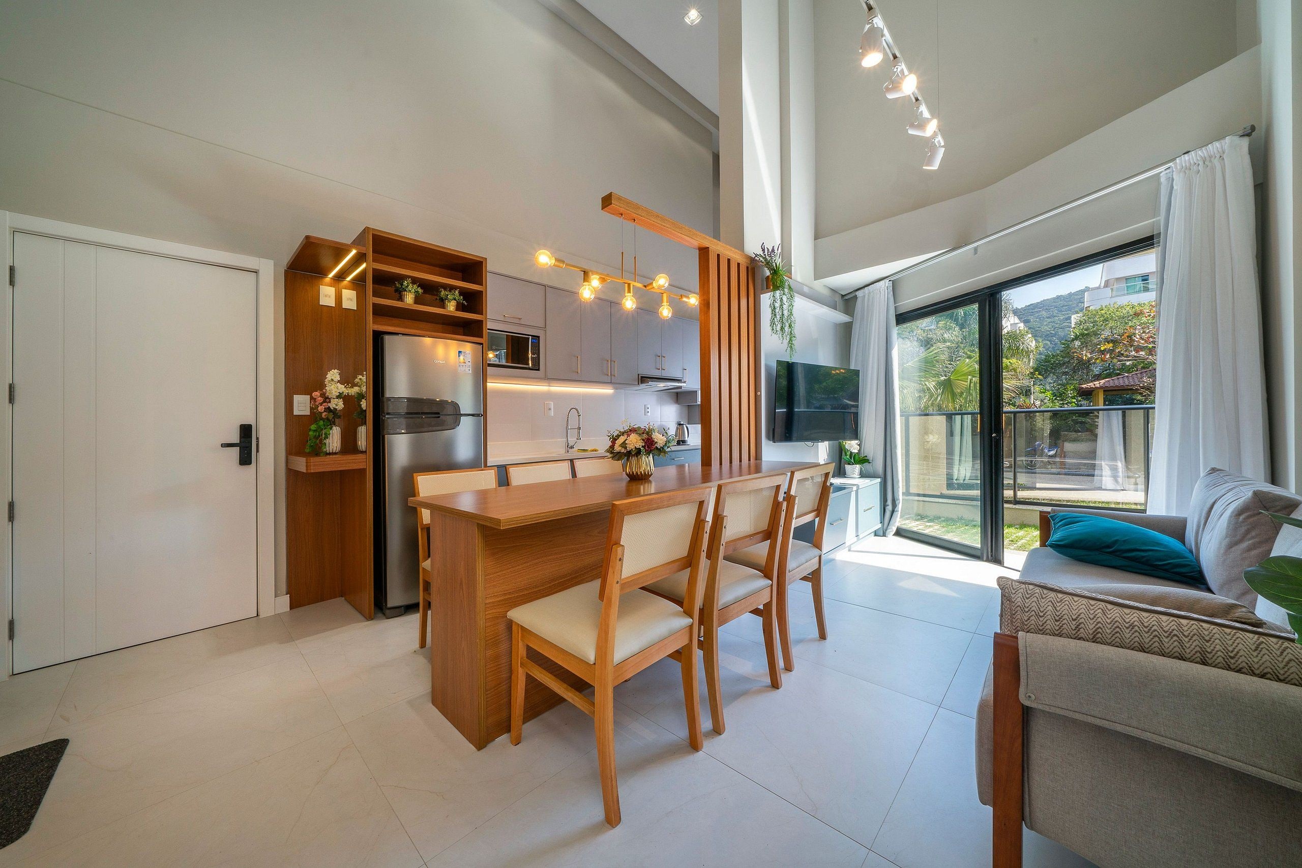 A modern kitchen with a wooden island, built-in appliances, and a large sliding glass door leading to a balcony.