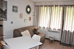 A modern living room with a sofa, a dining table, and a radiator.