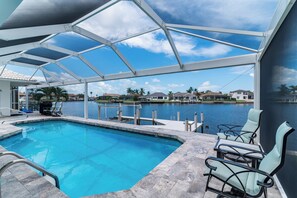 An indoor swimming pool with a view of a marina and houses across the water.