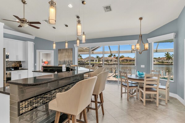 A modern kitchen with a large island, white cabinets, and a view of a lake.