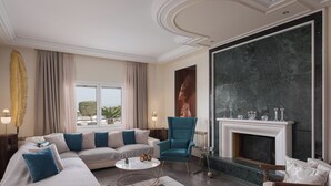 Una sala de estar moderna con un sofá modular, un sillón azul, una chimenea y un ventanal con cortinas.