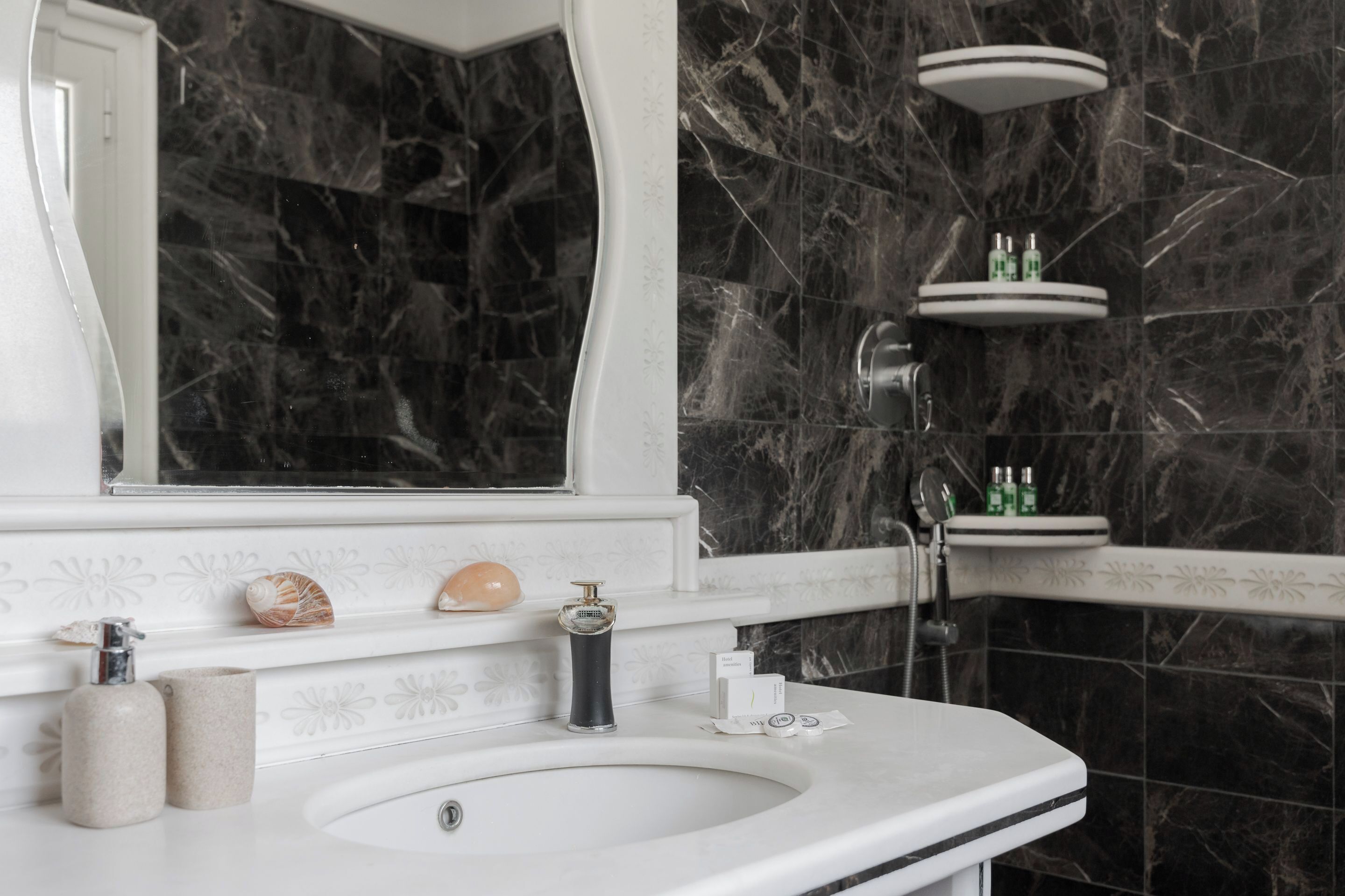 A bathroom with a marble sink, a mirror, and a shelf with toiletries.