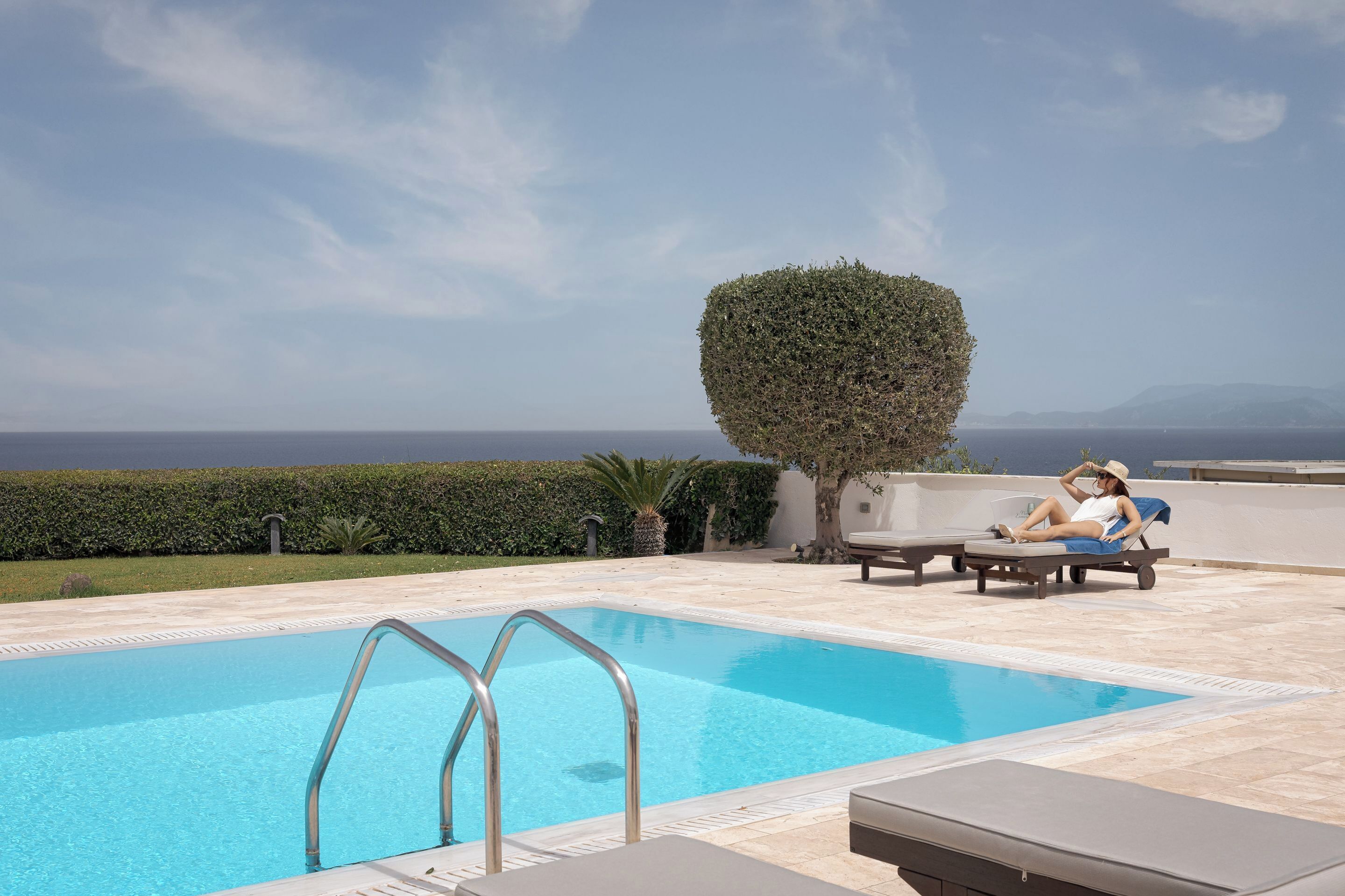 A swimming pool with a clear view of the sea and mountains in the background.