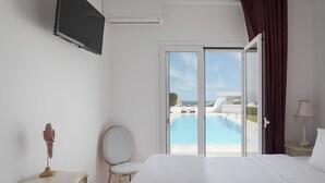 Un dormitorio con cama, una silla, un televisor montado en la pared y vistas a una piscina a través de un ventanal.