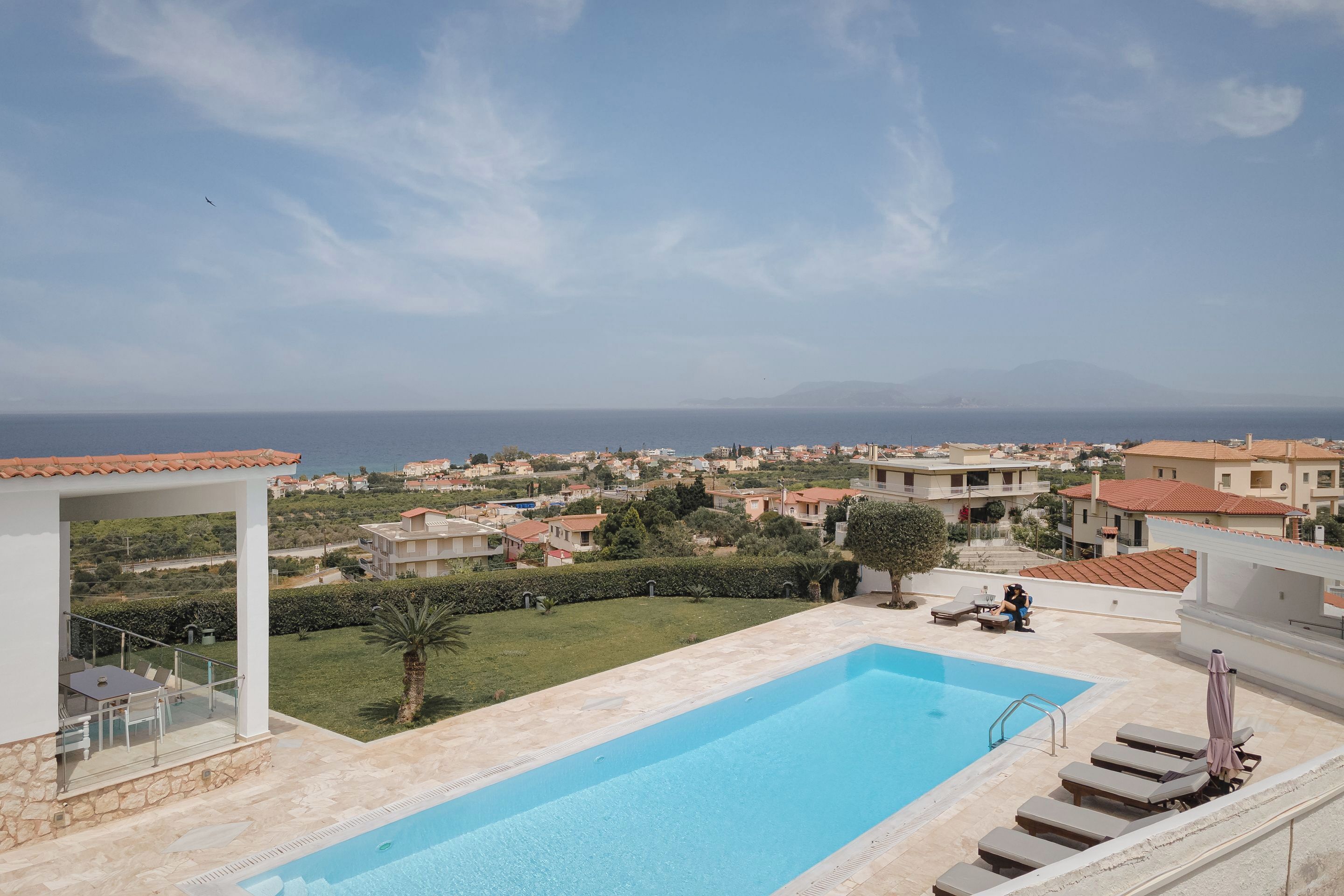 Piscina com vista para o mar e casas ao redor.