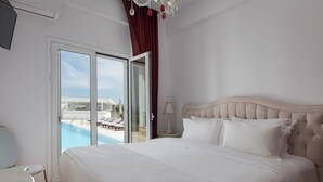 Habitación de hotel con una cama grande, puerta corredera de vidrio a un área de piscina y vistas a la piscina.
