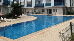 Ein modernes Apartmenthaus mit Schwimmbad, Balkonen und blauem Himmel.