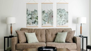 A living room with a brown sofa, two side tables with lamps, and three framed wall art pieces. - Chic Lancaster Vacation Rental, Walkable Location! (Lancaster)