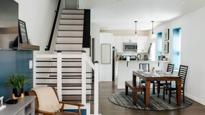 A modern kitchen with white cabinets, a microwave, and a dining area with a wooden table and chairs. - Chic Lancaster Vacation Rental, Walkable Location! (Lancaster)