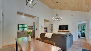Een moderne woonkamer met een houten eettafel, een grijze bank en een kroonluchter.