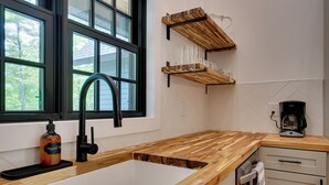 Een keuken met een houten aanrecht, een spoelbak en een koffiezetapparaat.