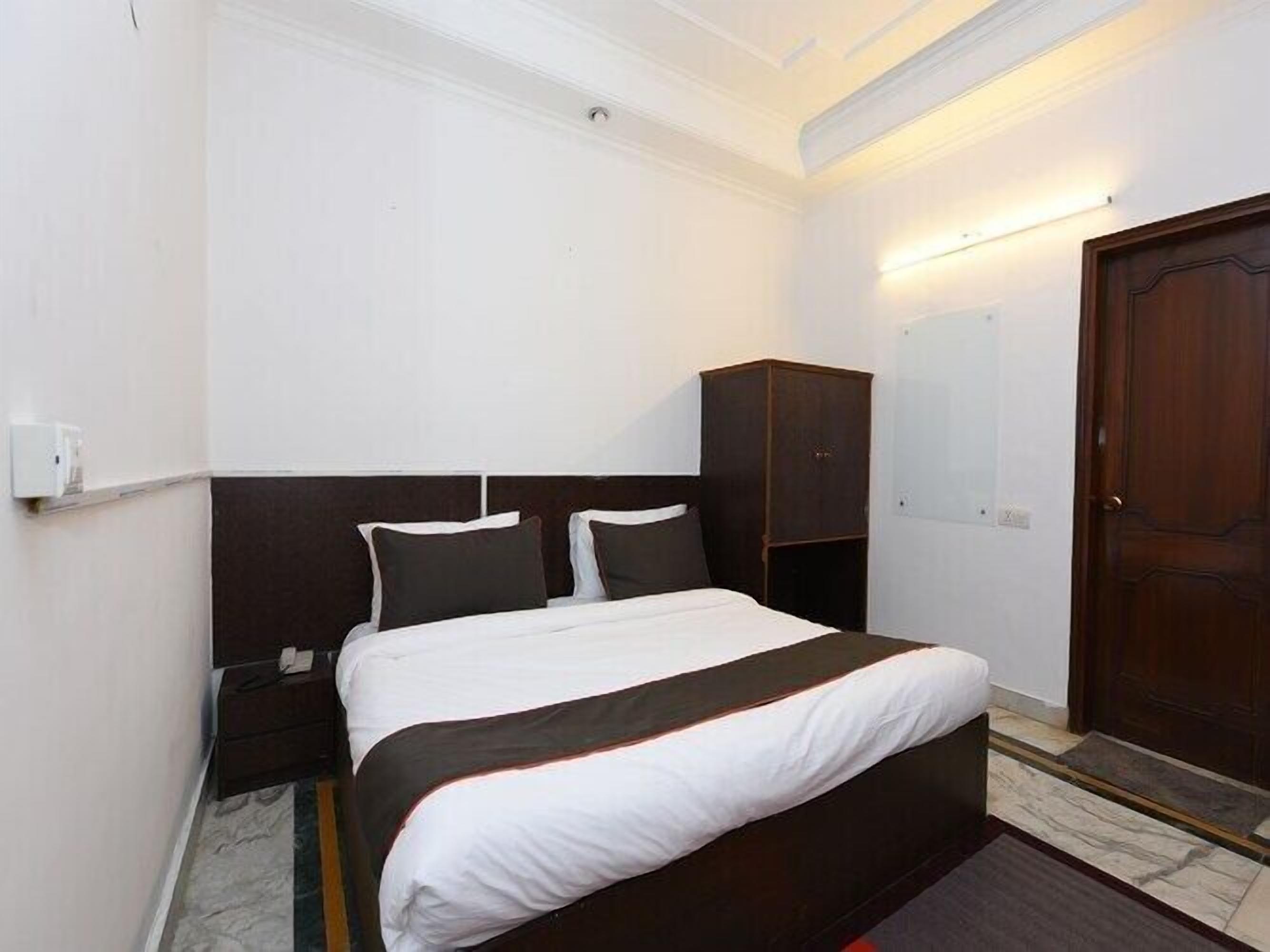Una habitación de hotel con cama, armario, mesita de noche y una puerta.