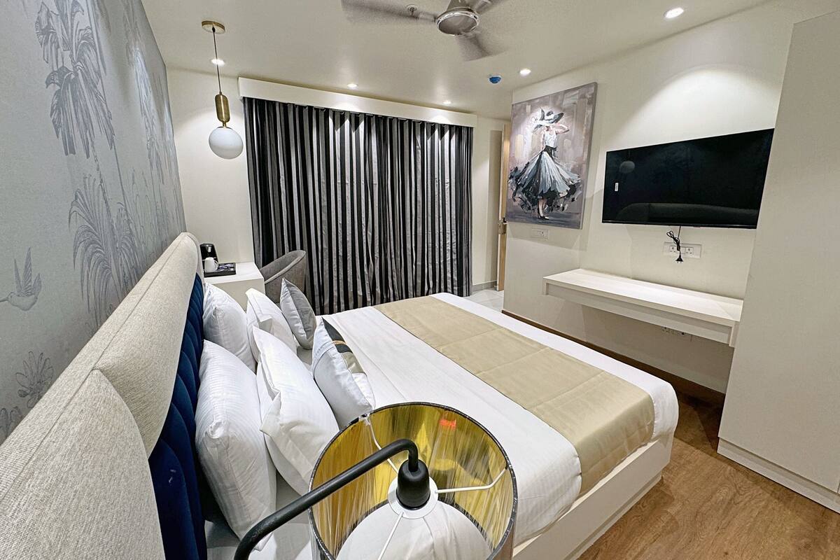 Ein modernes Hotelzimmer mit einem großen Bett, einem Deckenventilator, einem Flachbildfernseher und einem Gemälde an der Wand.