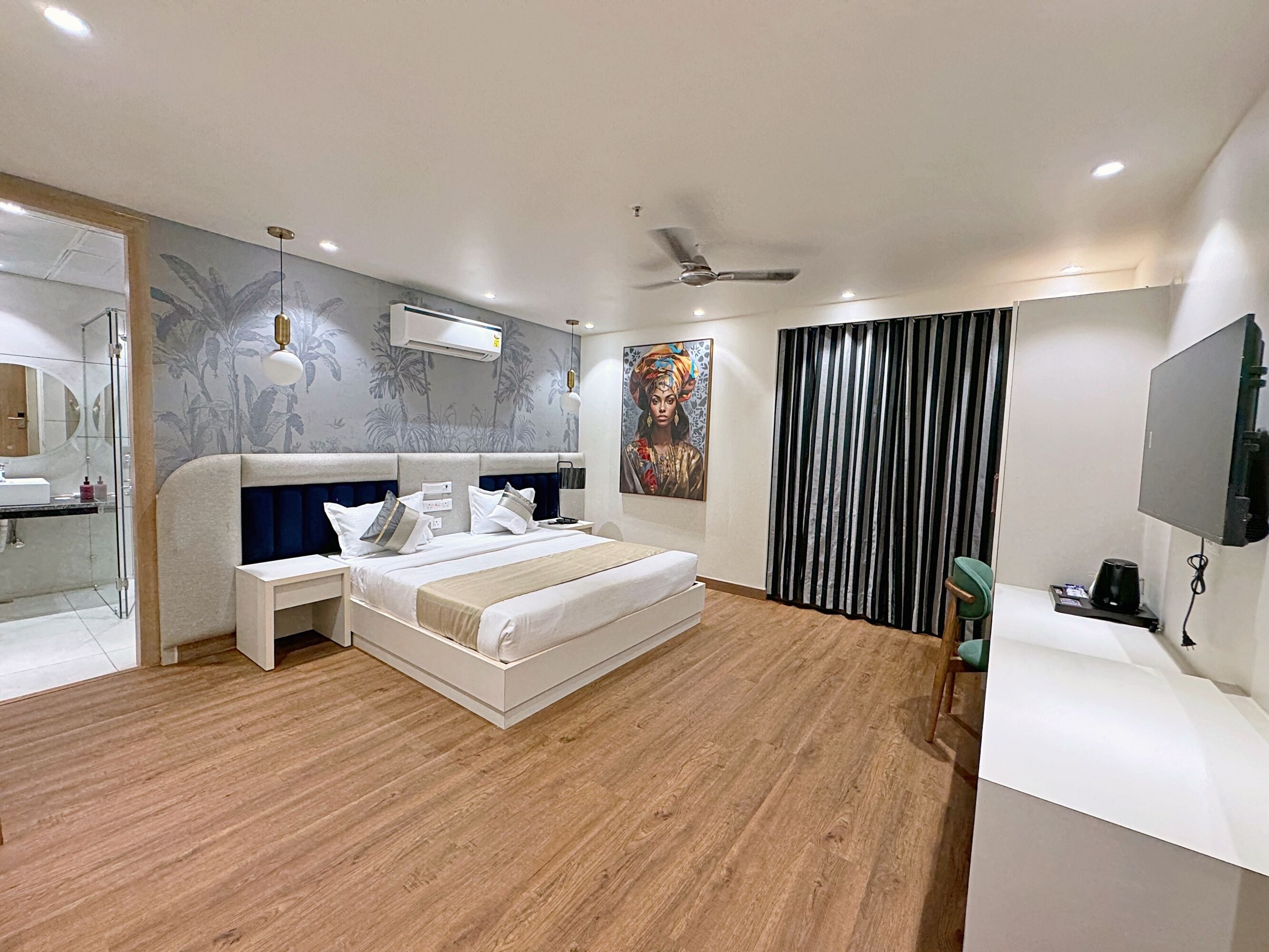 A modern bedroom with a large bed, a desk, and a television.