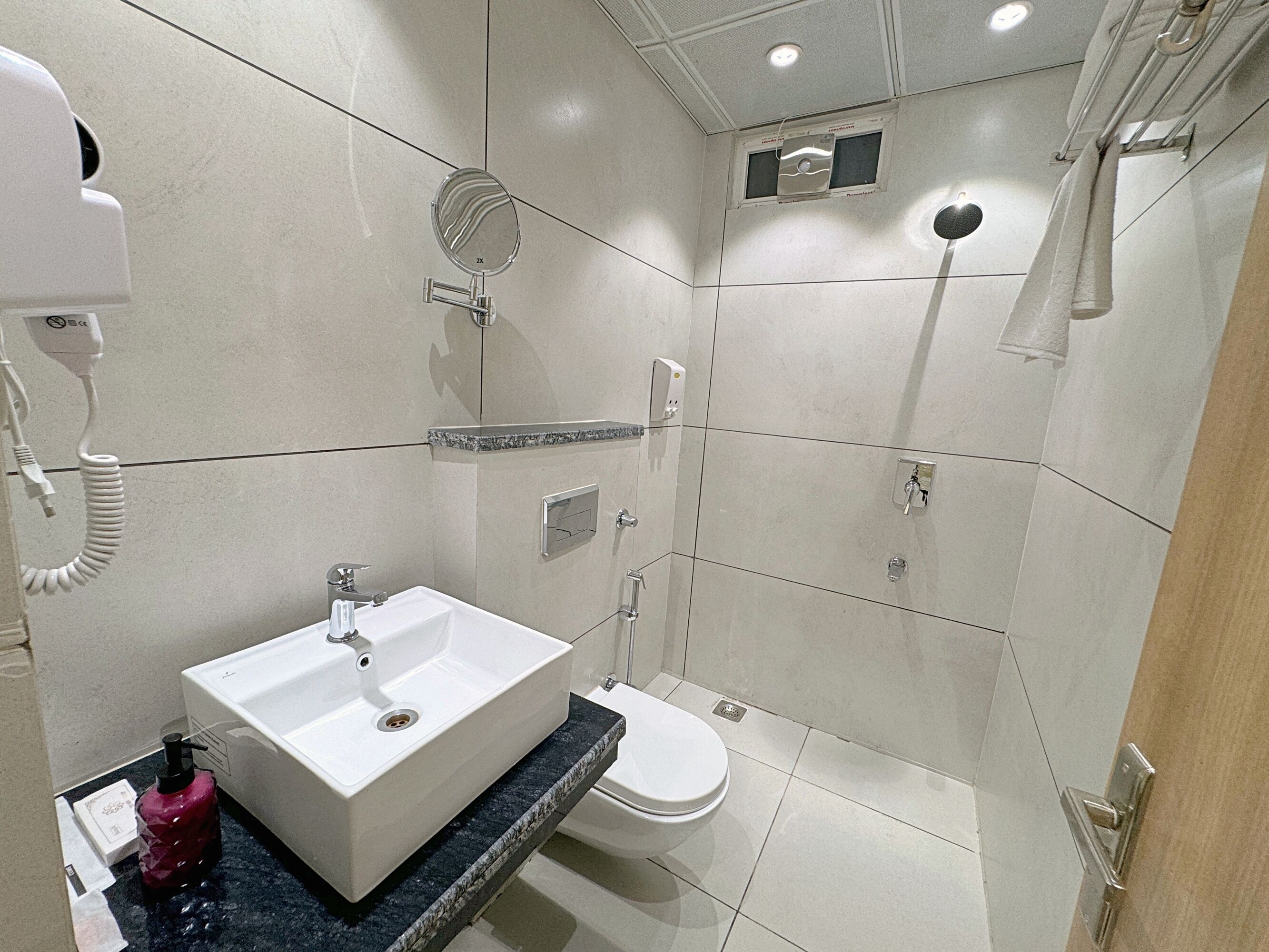 A modern bathroom with a white sink, toilet, and shower.