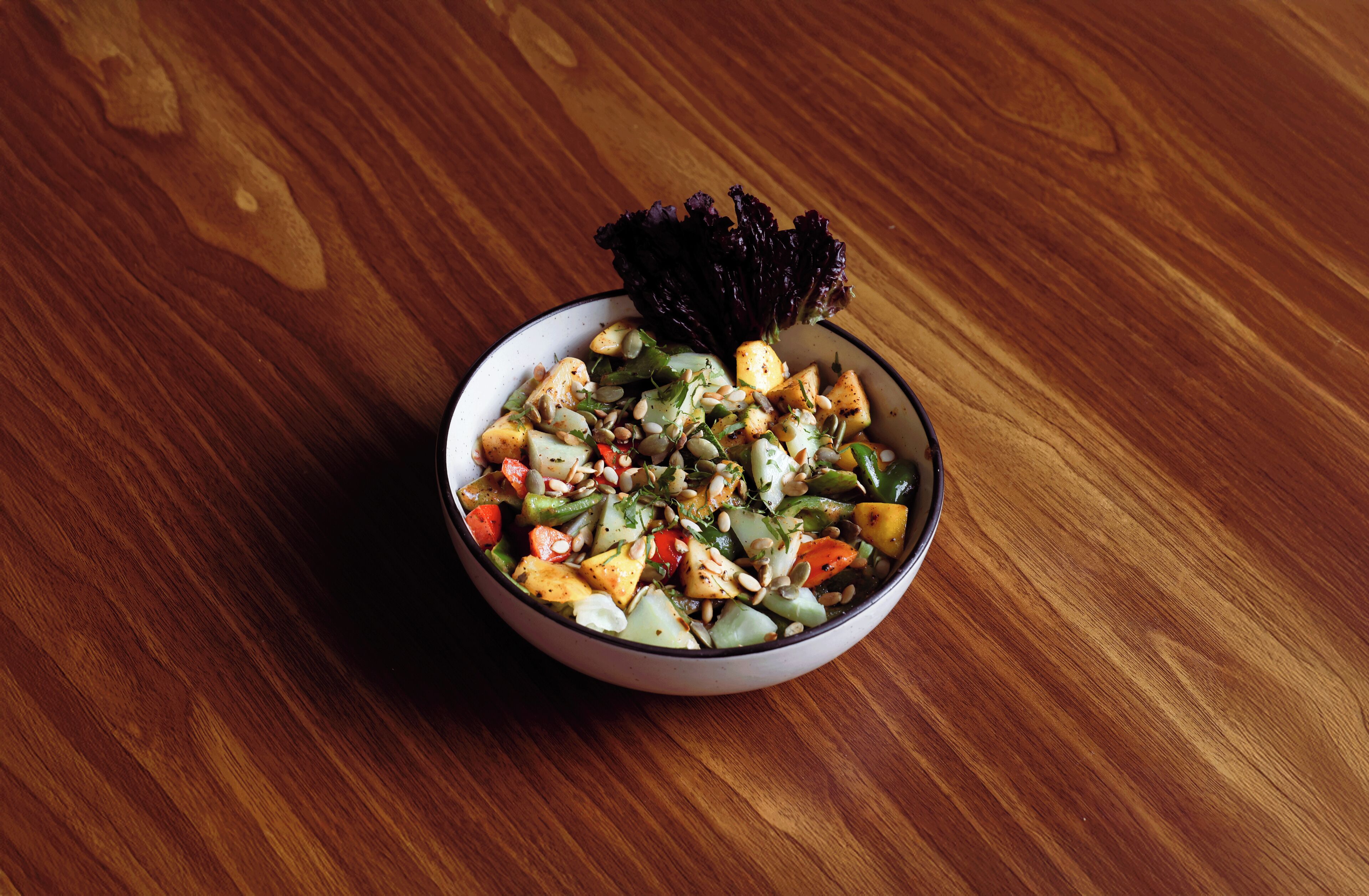 A bowl of salad on a wooden table.