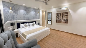 Una habitación de hotel moderna con una cama grande, un escritorio, una silla, un ventilador de techo y una pared con un mural floral.