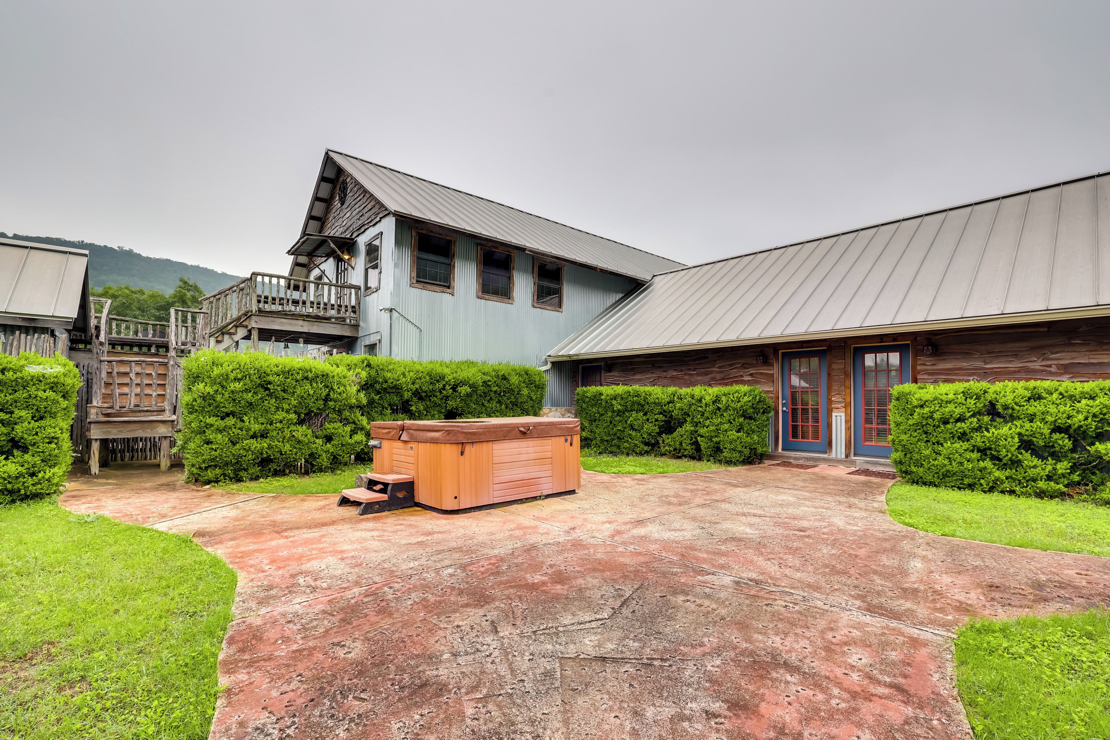 A building with a wooden deck, a hot tub, and a well-maintained lawn.