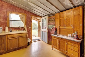 A rustic kitchen with wooden cabinets, a sink, and a window with curtains.