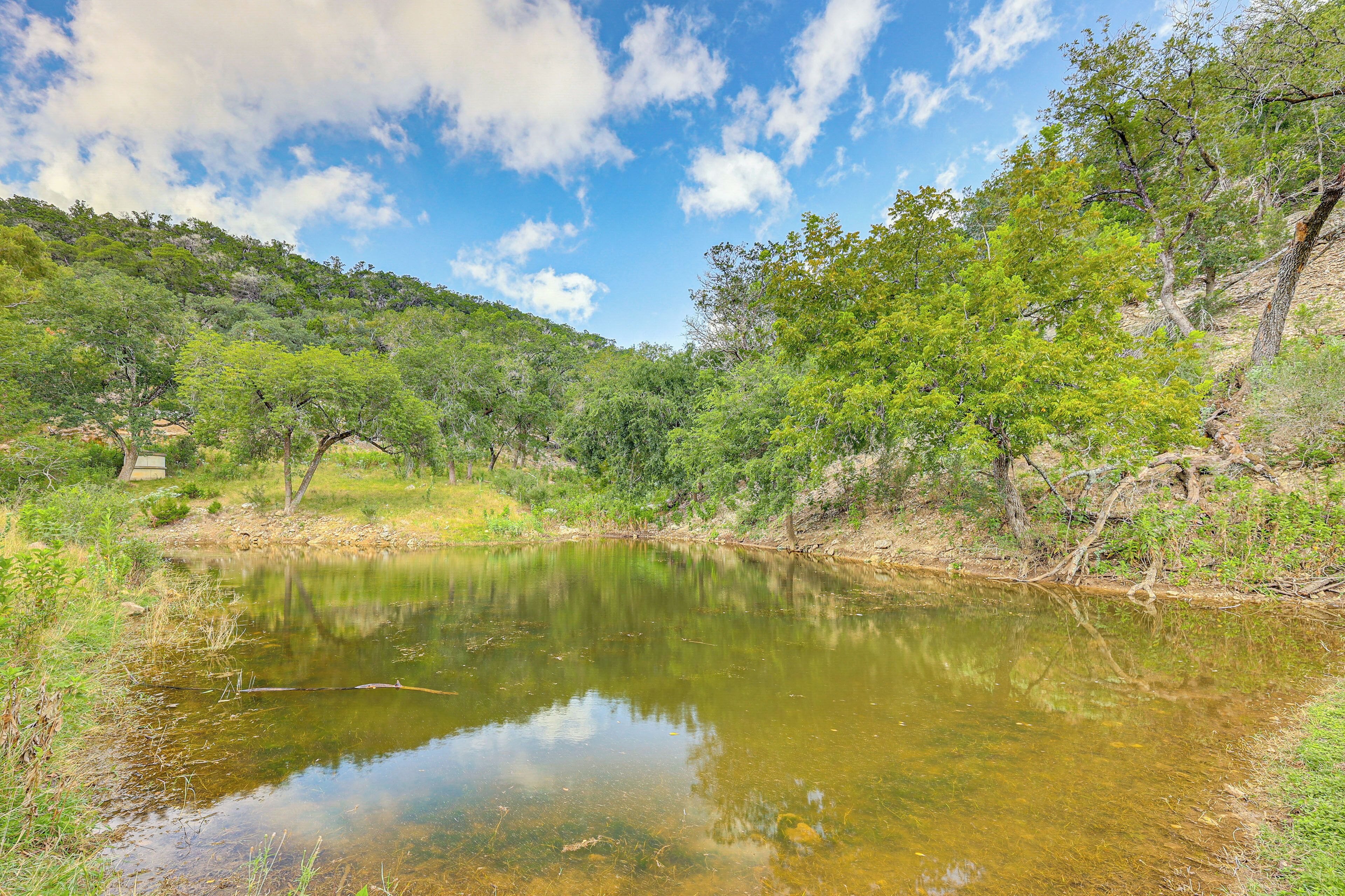 A natural landscape with a body of water reflecting trees and sky.