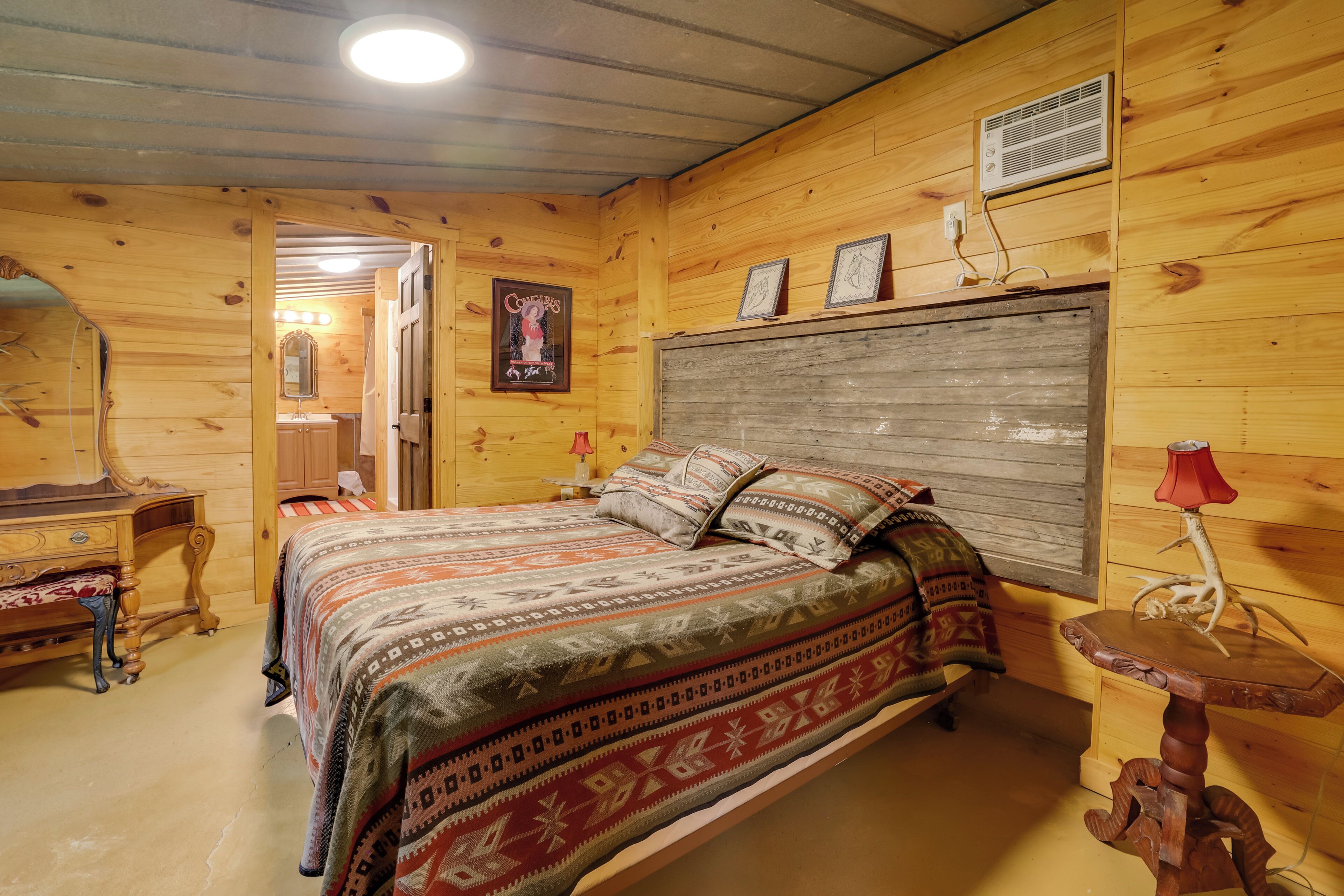 A wooden cabin bedroom with a bed, dresser, and a mirror.
