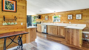 A modern kitchen with wooden paneling, a central island, and a dining table. - Sleep With Sloths & Lemurs! Modern Webster Home (Webster)