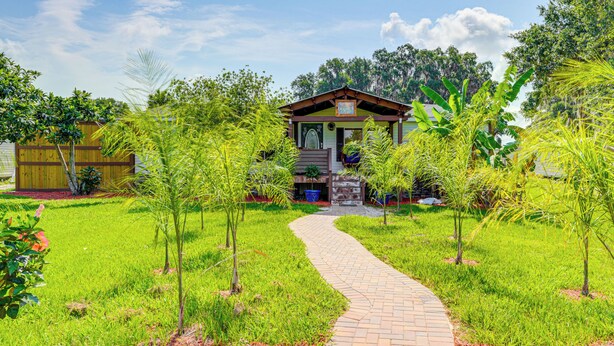 A pathway leading to a building with a signboard, surrounded by lush greenery and trees. - Sleep With Sloths & Lemurs! Modern Webster Home (Webster)