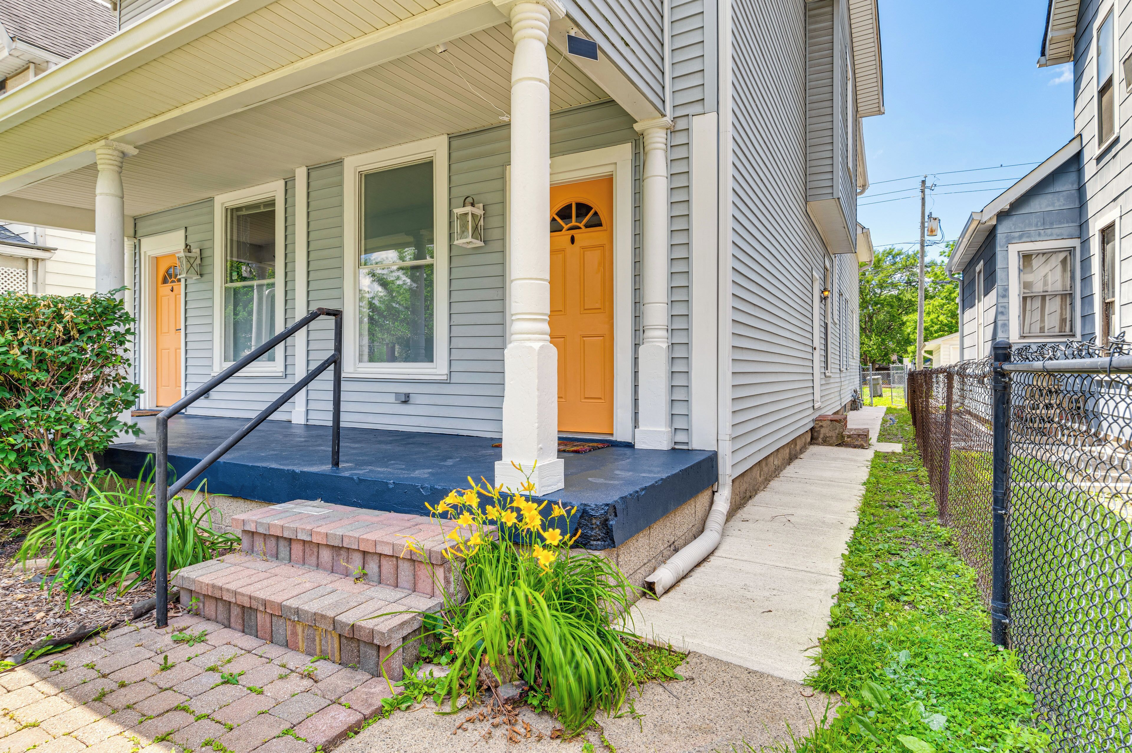 A house with a porch, a front door, and a small garden with flowers.