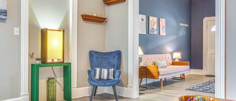 A hallway with a blue chair, a wooden console table, and a bowl on a wooden table.
