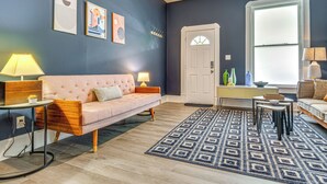 Ein Wohnzimmer mit einem rosafarbenen Sofa, einem Couchtisch und einem gemusterten Teppich.