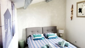 Ein Schlafzimmer mit einem großen Bett, einem Kopfteil, einem Nachttisch mit Lampe und einem Wandbild.