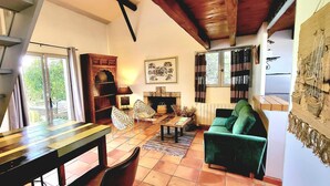 Ein gemütliches Wohnzimmer mit einer hölzernen Bank, einem grünen Sofa, einem Kamin und einem Essbereich mit Tisch und Stühlen.