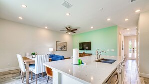 Una cocina moderna con una isla central, un comedor con sillas a rayas y un sofá azul.