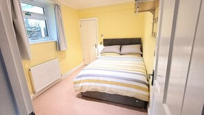 A bedroom with a bed, a window, a radiator, and a door. - 3 Room Bedsit Flat in Nat. Reserve. Pet friendly. Free return Eden taxi B4 9pm. (Par)