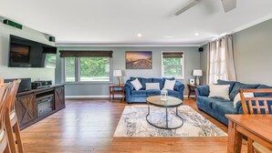 A spacious living room with a blue sofa, a coffee table, and a wooden dining table.