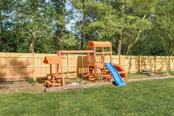 A wooden play structure with a slide in a backyard.