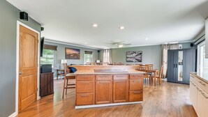 A spacious kitchen with a large island, wooden cabinets, and a dining area with chairs.