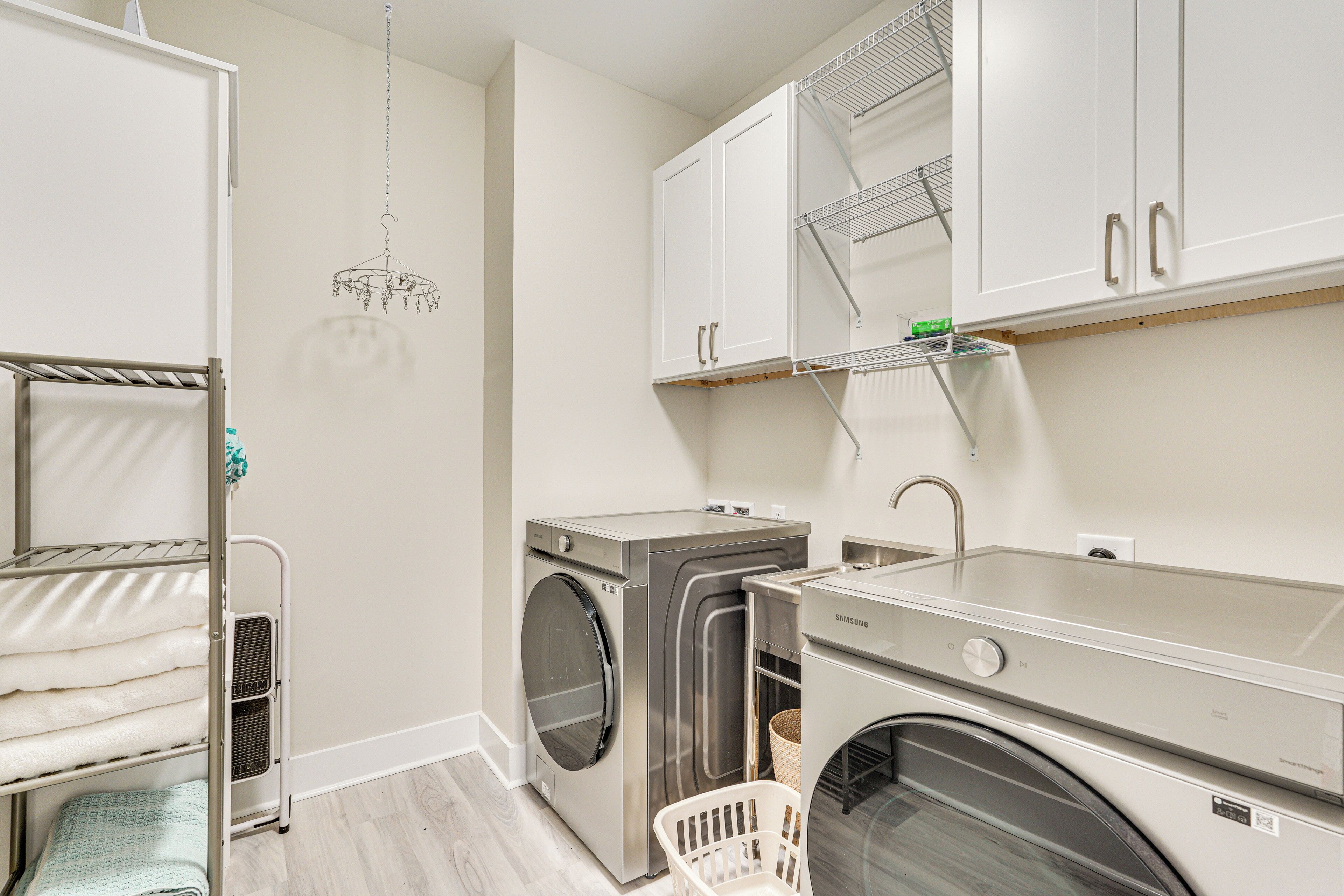 A compact laundry room with a washing machine, dryer, and a drying rack.