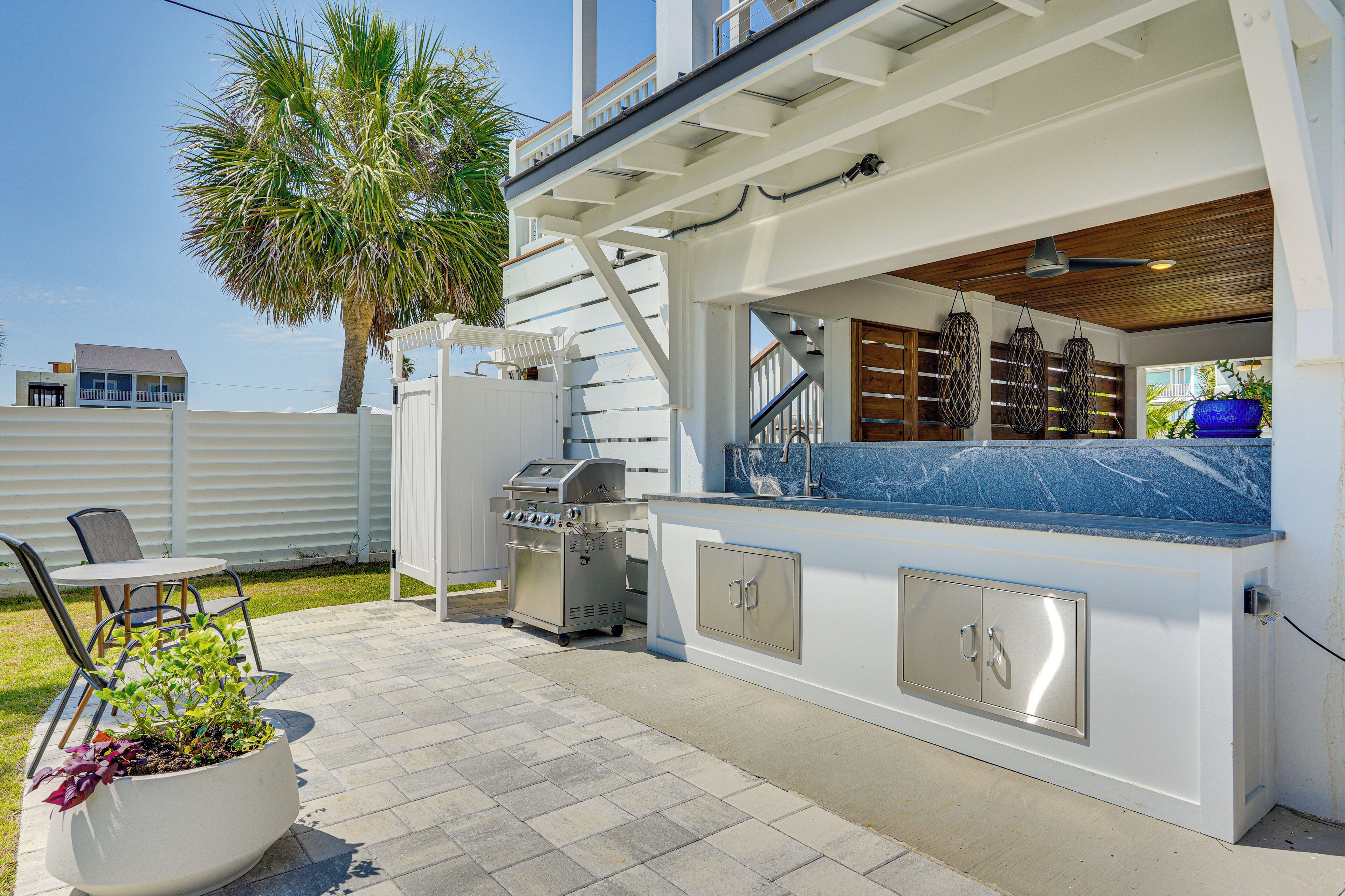 Un espace cuisine extérieur comprenant un barbecue, des sièges et un grand bac à plantes.