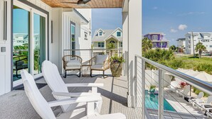 Un balcon avec des chaises blanches, une piscine et une vue sur les maisons voisines.