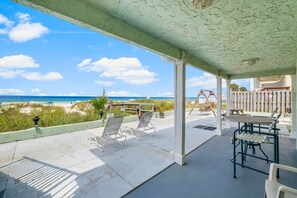 A covered outdoor area with a view of the beach, including lounge chairs and a table. - FREE Golf&Perks! Updated, Cozy Beachfront Bargain, Amazing Views, Pool&Grills (Panama City Beach)