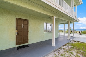 A building with a brown door, a window, and a covered porch area.