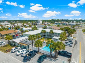 A hotel with a pool, multiple parking spaces, and a view of the surrounding neighborhood.