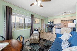 A compact living space with a dining area, a sofa, a kitchen, and a view of the outside.
