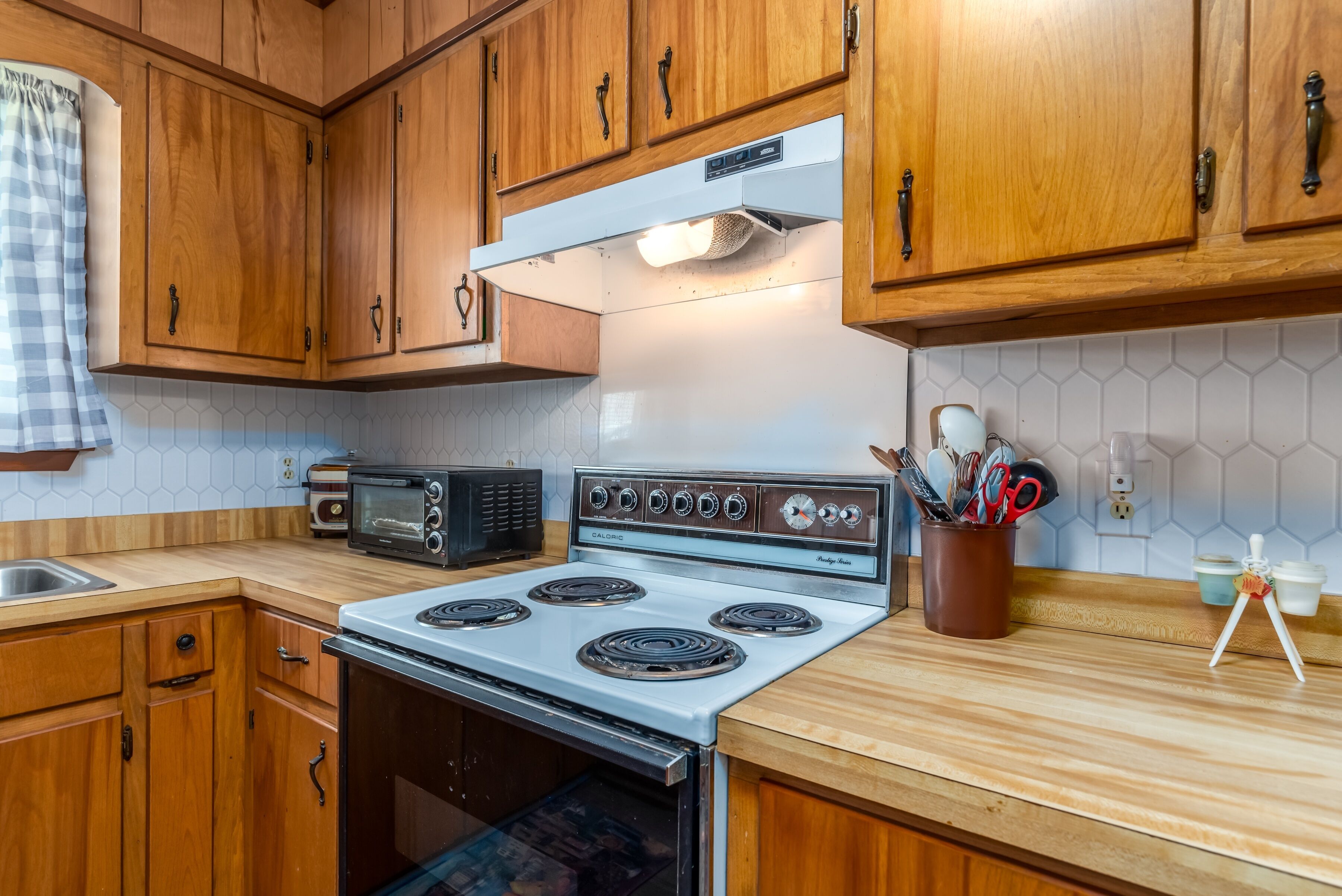 A kitchen with wooden cabinets, a white stove, a microwave, and a toaster.