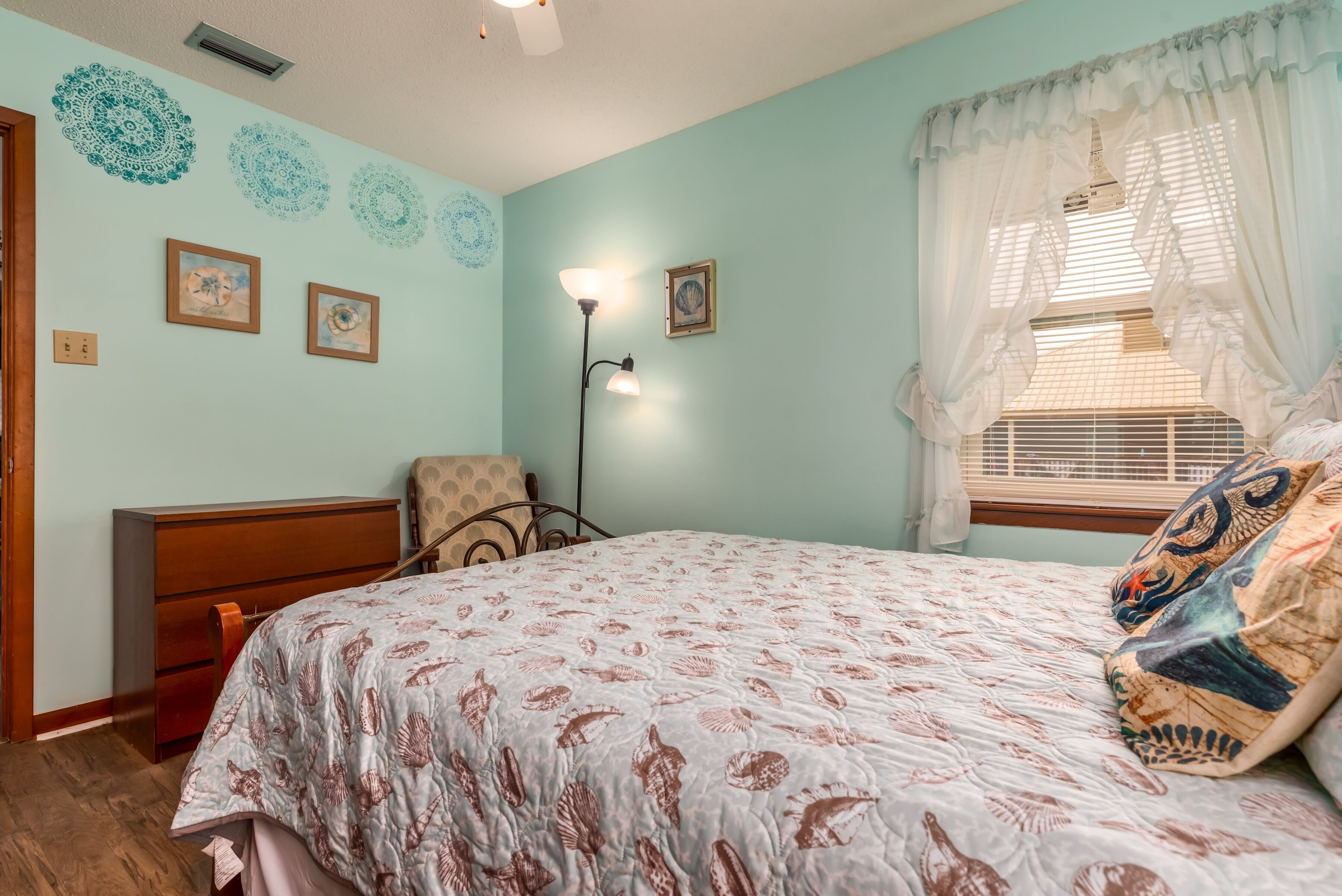 A bedroom with a bed, a nightstand, a lamp, and a window with curtains.