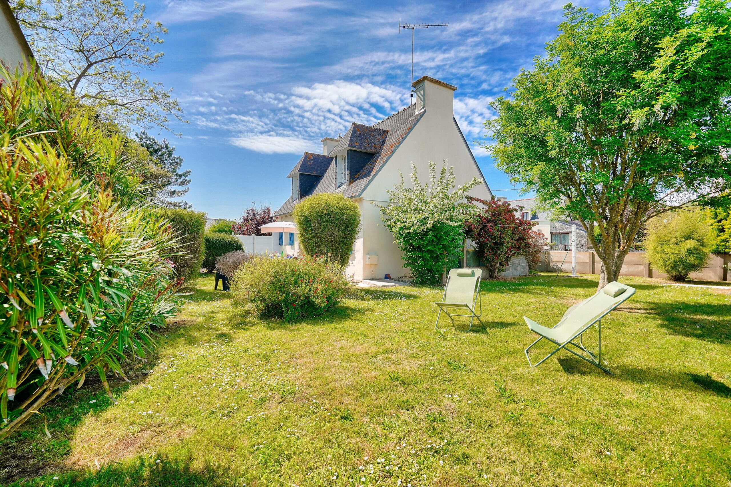 A house with a sloped roof, a visible chimney, and a lawn with a lawn chair.